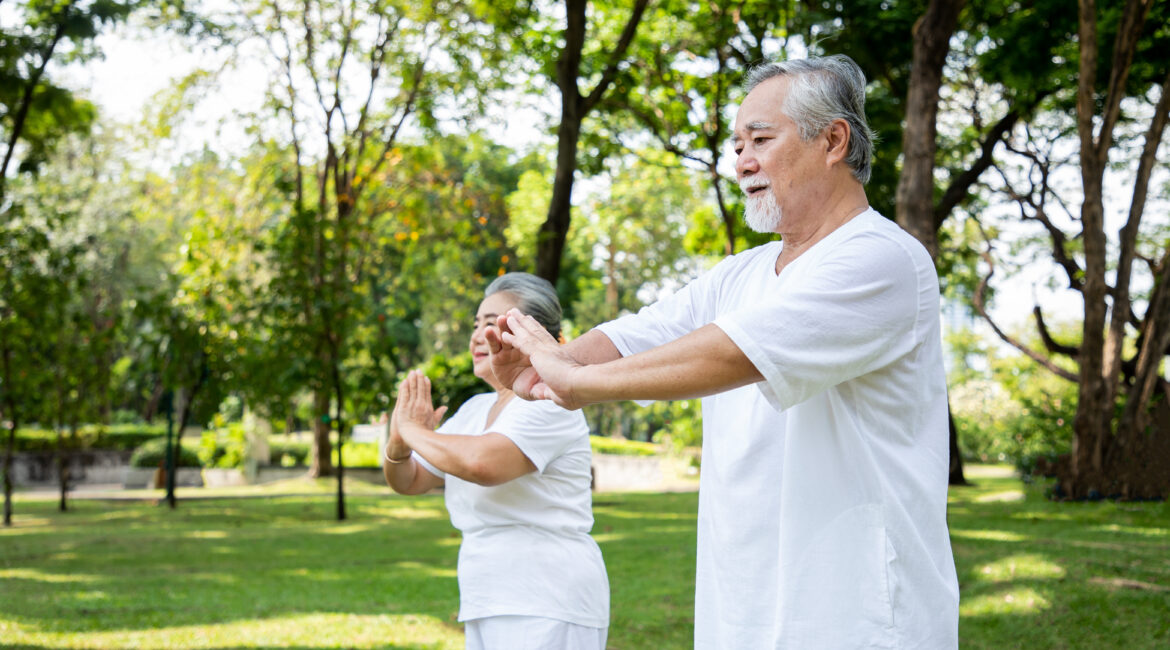 An elderly couple doing yoga lesson and Tai Chi in the garden with smiles brightly and enjoys from exercise.  Healthy insurance and relaxation after retirement concept.
