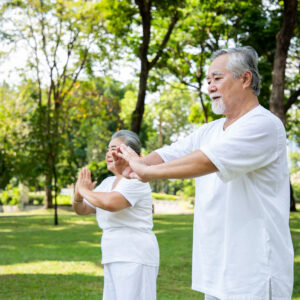 An elderly couple doing yoga lesson and Tai Chi in the garden with smiles brightly and enjoys from exercise.  Healthy insurance and relaxation after retirement concept.